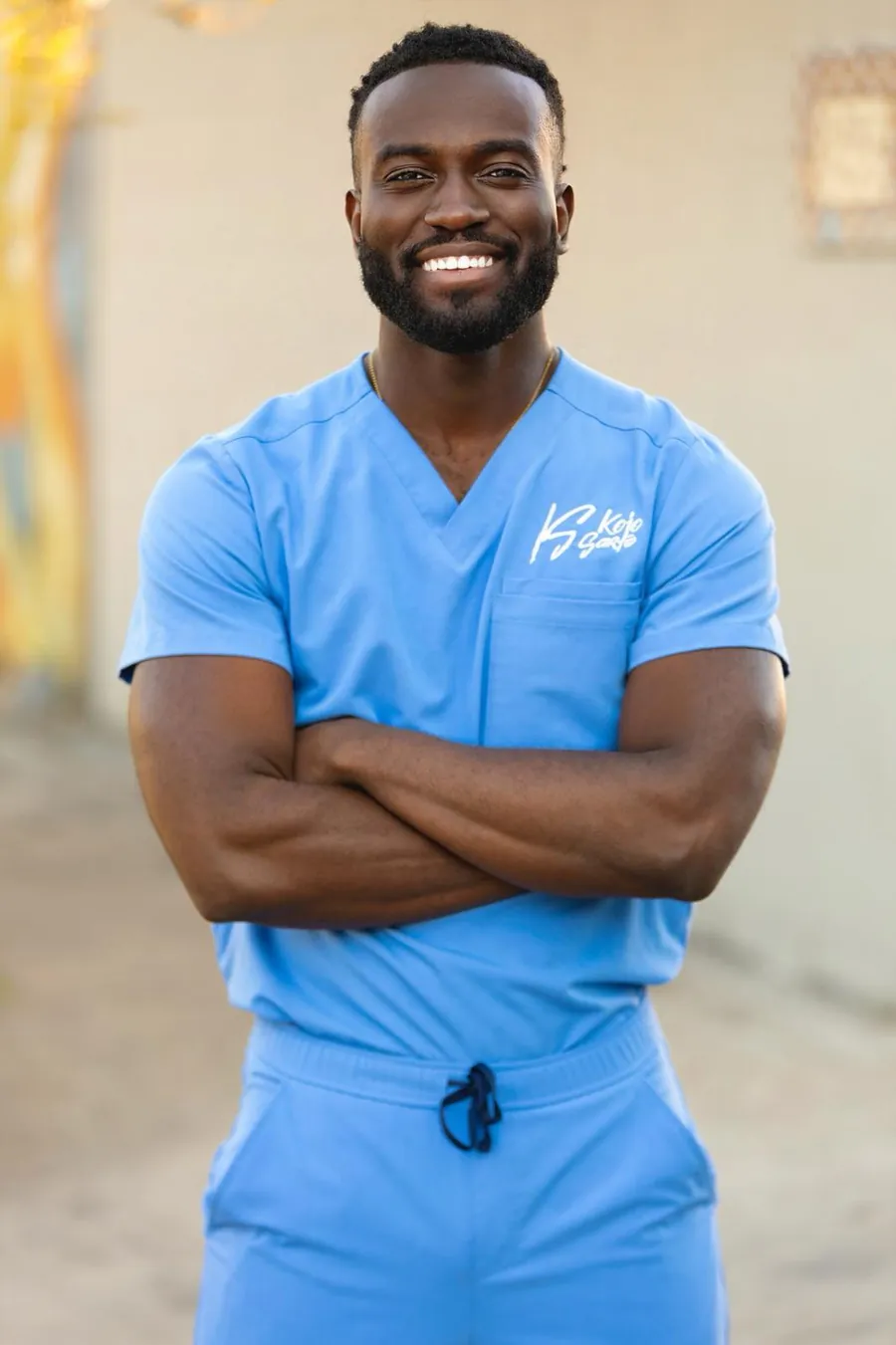 Dr. Kojo in scrubs with his KS signature logo on the chest